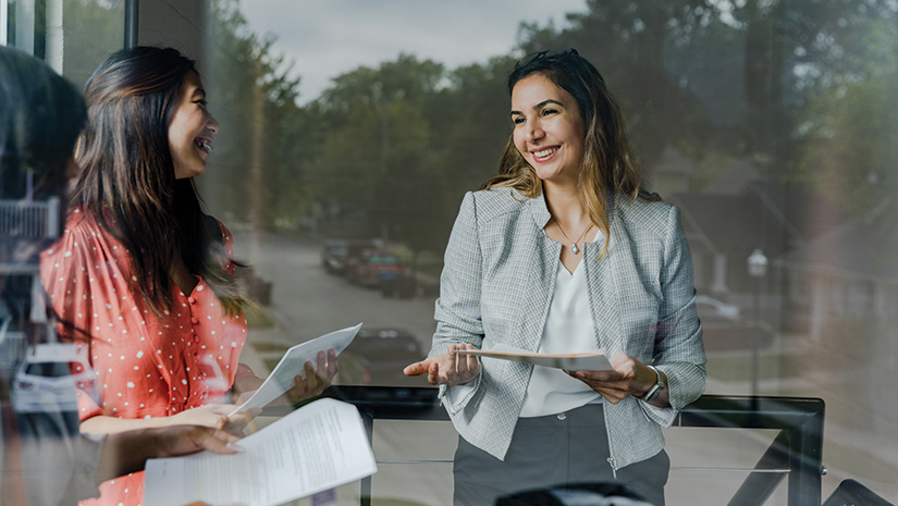 Businesswomen discuss documents during meeting
