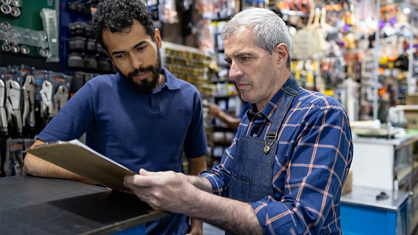 Business owner training a new hire at a hardware store