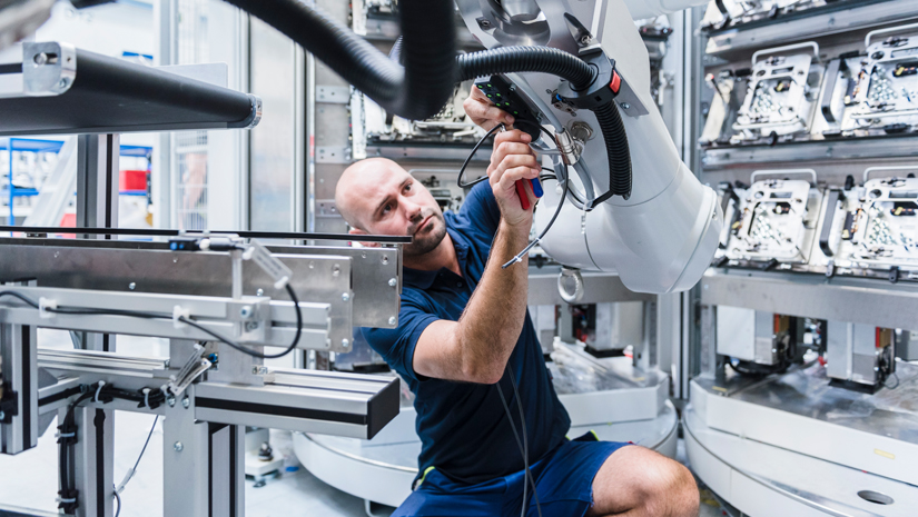 Robot mechanic working on arm of robot.