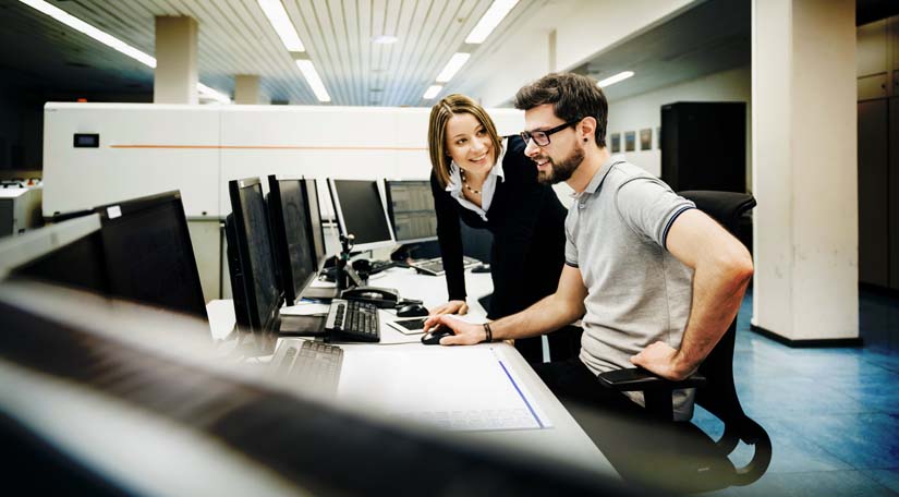 Two IT professionals looking at equipment in control room