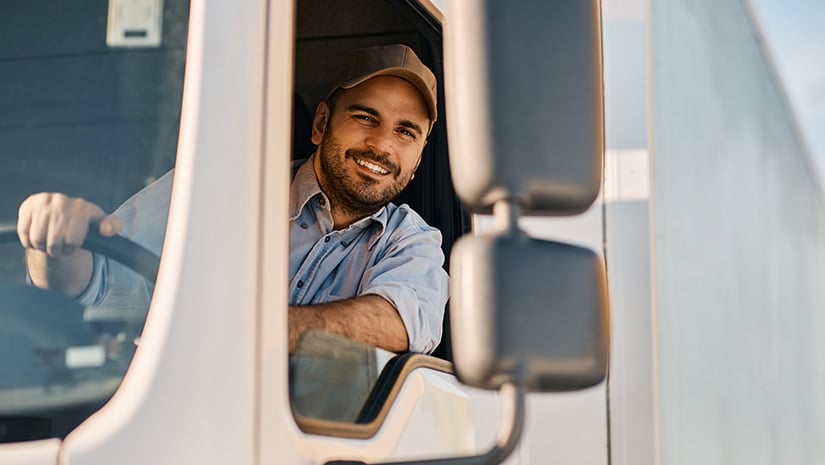 Happy truck driver looking through side window while driving his truck