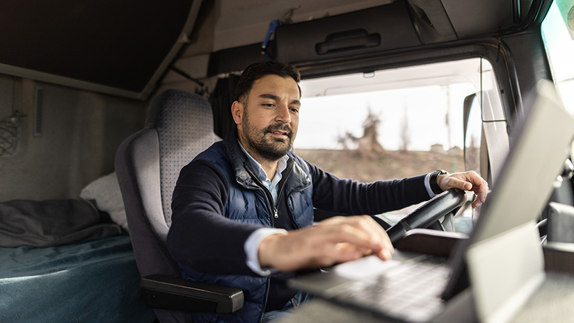 Truck driver typing destination on tablet while sitting in cabin