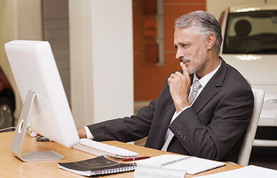Focused Car Dealer Looking at Computer