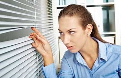 Suspicious Businesswoman Peering Through Blinds